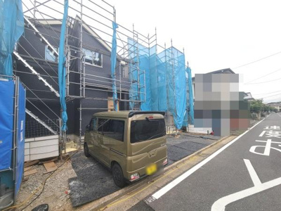 目の前に幅広い道路があり車の出し入れがしやすい現地写真です。前面道路の状況や幅員が確認でき建物の外観も分かりやすいです。駐車スペースも明確に映っています。建物の建築状況も見て取れる写真です。