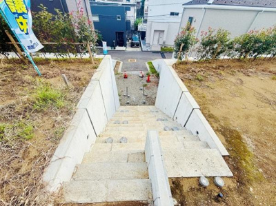 コンクリート造りの階段が敷地内に設置されており段差の上り下りがしやすい構造です。手すり付きで安心してご利用いただけます。周囲には緑が植えられており季節の変化も楽しめます。