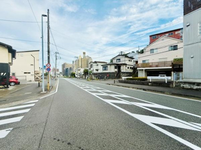 幅の広い道路が特徴的で見通しも良好です。周辺には住宅やマンションが並び落ち着いた街並みが広がっています。歩道もしっかり整備されており利便性を感じられる環境です。青空が広がり開放感も印象的です。