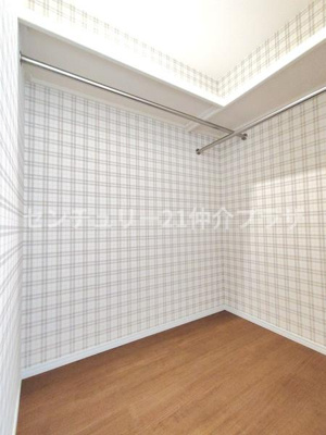 シンプルなデザインの収納スペースです。壁紙の柄が空間にアクセントを加えています。ハンガーパイプが2本設置されており衣類の管理に便利です。天井までしっかり高さがあり収納力も期待できます。