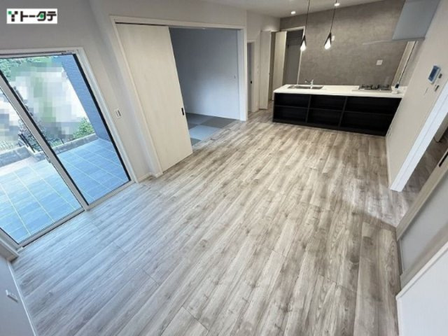 グレーがかった木目調のフローリングと高級感のあるキッチン背面のアクセントクロスがマッチしたLDK。