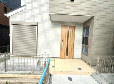 玄関はスッキリとした外観となっており落ち着いた色合いが印象的です。玄関前のスペースもゆとりがあり出入りがしやすいつくりです。ウッド調のドアがアクセントになっています。防犯面にも配慮された設計です。