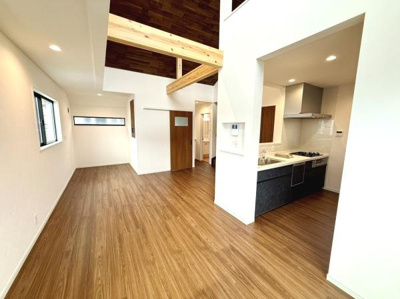 開放感のあるリビングが広がっています。木目調の床が空間に温かみをプラスしています。天井の梁が印象的でデザイン性の高さが窺えます。キッチンとリビングが程よく区切られた間取りが特徴的です。