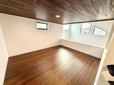 木目調の天井が印象的な洋室です。複数の窓から自然光が差し込み明るい空間となっています。壁面のホワイトカラーが室内を広く感じさせます。床は落ち着いた色合いですっきりとした印象です。