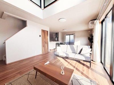 大きな窓から光がたっぷり差し込むリビングです。木目調のフローリングが空間を明るくしています。吹き抜け天井が開放感を与えています。シンプルな内装がさまざまなインテリアに合います。