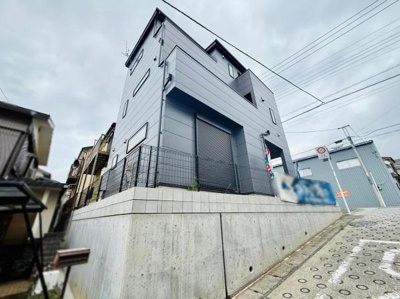 スタイリッシュな外観が印象的な建物です。コンクリート塀により敷地がしっかりと区画されています。前面道路はゆるやかな坂となっており周囲との高低差が特徴です。周辺の建物との距離も確保されています。