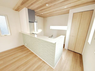 明るい色合いのフローリングと天井が空間を広く感じさせます。キッチンカウンターのタイルがアクセントになっています。複数の窓が採光をしっかり確保しています。