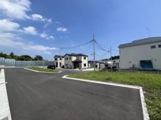 前面道路は幅員がしっかり確保されており車の出入りもスムーズに行いやすい環境です。晴れた日には空が広がり開放感を感じられる現地写真です。周囲は整備された住宅地で落ち着いた雰囲気が漂っています。