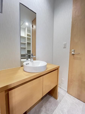 木目調の洗面台が落ち着いた雰囲気を演出しています。シンプルなデザインで空間がすっきりとまとまっています。大きめの鏡が空間を広く見せてくれます。収納スペースも備わっており使い勝手にも配慮されています。