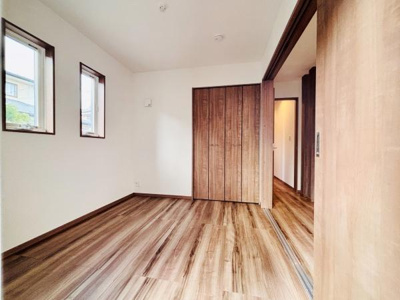 木目のフローリングと建具が統一感を演出しています。二面採光のため室内が明るい印象です。収納スペースも備わっておりすっきりと使えます。落ち着いた色調の洋室です。引き戸で室内の使い方も自由度があります。