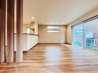 広々としたリビング空間が広がっています。床材の木目が温かみを演出しています。大きな窓からたっぷりと自然光が差し込みます。キッチンとの一体感も感じられる設計です。室内が明るく開放的な印象です。