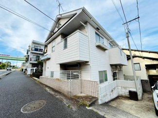 道沿いに建つ白を基調とした外観が印象的です。複数のバルコニーがあり各部屋に採光が期待できます。角地に位置しているため外観の開放感が感じられます。敷地のフェンスや塀がしっかりと設けられています。