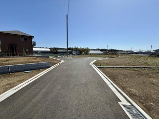 前面道路に面した現地の広がりが感じられる写真です。周辺は開放感があり敷地の様子がよくわかります。陽当たりにも恵まれた明るい印象の一枚です。道路幅にもゆとりがあり現地のアクセスのしやすさが伝わります。