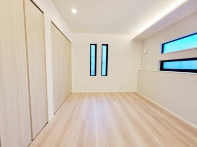 リビングは明るい色合いのフローリングが特徴です。縦長の窓が空間に開放感を与えています。収納スペースも用意されており整理がしやすい造りです。天井の照明がシンプルな雰囲気にマッチしています。