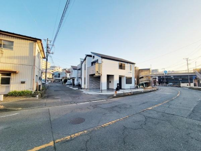 現地の様子がしっかりと確認できる前面道路の写真です。周辺の建物との位置関係も分かりやすく見通しの良い道路沿いに立地しています。角地の特徴が写真からも伝わります。