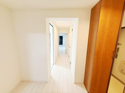 白を基調とした明るい廊下は清潔感があります。奥行きのあるデザインが印象的です。収納スペースもすっきりまとまっています。直線的なラインが空間の広がりを演出しています。ドアや床の色が統一感を感じさせます。