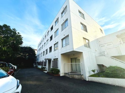 白を基調とした外観が印象的な建物です。敷地内に駐車スペースが確保されています。複数の窓があり採光にも配慮された設計です。周囲の緑も程よく落ち着いた雰囲気です。共用部分も清潔に保たれています。