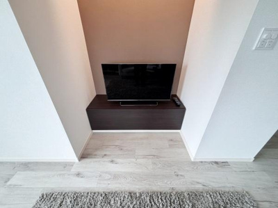 落ち着いた色合いの壁と床がリビングに調和をもたらします。テレビ台の設置スペースが確保されすっきりとした印象です。フローリングの質感が空間の雰囲気を高めます。