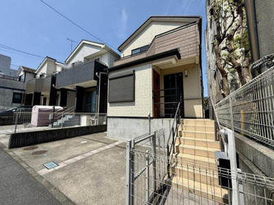 シンプルな外観が印象的な一戸建てです。玄関までのアプローチがゆったりと設計されています。敷地内には駐車スペースも確保されています。前面道路との高低差があり落ち着いた雰囲気が感じられます。