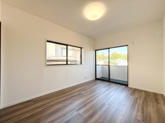 大きな窓からたっぷりと自然光が入る洋室です。明るく開放的な空間が広がります。木目調のフローリングが印象的です。バルコニーへのアクセスも便利です。シンプルな内装でコーディネートしやすい点も魅力です。