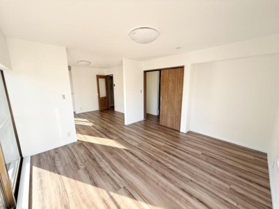 広々としたリビングには温かみのある木目調のフローリングが採用されています。大きな窓からたっぷりと自然光が差し込み明るい空間が広がります。シンプルな内装でお好みのインテリアを楽しめます。