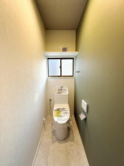 落ち着いた色合いの壁が印象的なトイレです。窓付きで換気しやすく清潔感のある空間が広がります。シンプルなデザインで手入れがしやすい仕様です。壁面に設置されたペーパーホルダーも使いやすいです。