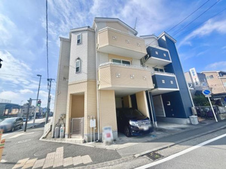 三階建ての外観が印象的な住宅です。ベージュとホワイトのカラーが明るく清潔感を感じさせます。バルコニー付きで通風や採光にも配慮されています。ガレージスペースも確保されています。