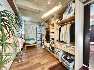 開放的な収納スペースがベッドルームの使い勝手を高めています。天井のコンクリートと木目の床がスタイリッシュな雰囲気を演出します。奥行きのある空間で整理整頓がしやすそうです。インテリアの自由度も魅力です。