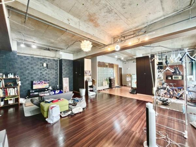 開放感のあるリビングが広がっています。天井はコンクリートの素材感が際立ち個性的な雰囲気です。ゆったりとしたスペースで家具のレイアウトも自由に楽しめます。