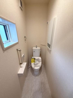 コンパクトな空間に窓が設けられ採光と換気に配慮されたトイレです。手すりや収納スペースも設置され使いやすさが感じられます。設備が整ったトイレとなっています。