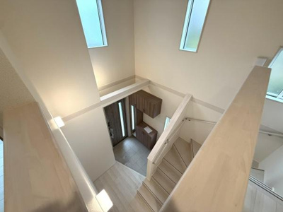 吹き抜けから差し込む自然光が空間全体を明るく包みます。すっきりとしたデザインの階段が印象的です。収納スペースが玄関に設置されており使い勝手の良さを感じます。開放的な雰囲気が室内を広く見せます。