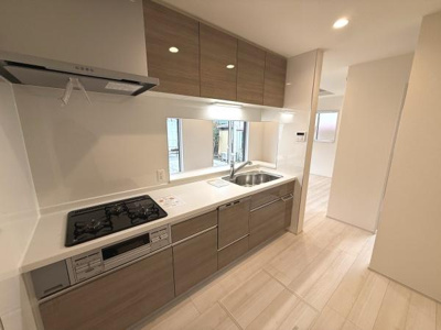 収納スペースが充実したキッチンとなっております。使いやすいシンプルな動線がポイントです。三口コンロで調理の際も便利です。