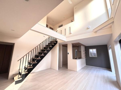 吹き抜けのある開放的なリビングが魅力的です。大きな窓からたっぷりと光が入ります。シンプルで洗練されたデザインが印象的です。階段や手すりのブラックカラーが空間を引き締めています。