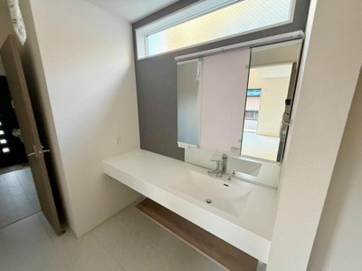 洗面台・洗面所は明るい窓があり自然光がしっかり入ります。広々としたカウンターも使いやすい設計です。すっきりとしたデザインで清潔感があります。鏡も大きめで身だしなみに便利です。