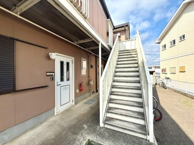 外階段が設置されたシンプルな外観の建物です。玄関周りには照明やポストが備わっています。共用部分がしっかりとした造りで日当たりも良好です。隣接する駐輪スペースも利用できます。