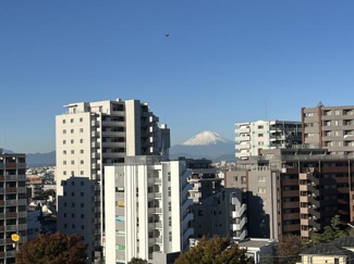 晴天の空と並ぶ高層マンションの間から富士山を望むことができます。日常の中で季節の移り変わりを感じられる景色となっています。周辺には緑もあり都市と自然が調和しています。開放的な眺望が魅力です。