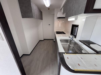 シンプルで使いやすい直線型キッチンです。上下のキャビネットが備わっており収納に便利です。ワークトップが広くお料理の準備もスムーズに進みます。落ち着いたカラーの床材が空間に調和しています。