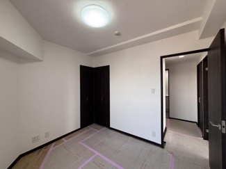 シンプルな内装が特徴の洋室です。落ち着いた色合いの建具が空間に統一感を与えています。収納が備え付けられており使い勝手の良いお部屋です。照明が天井に設置されており明るさを確保しています。