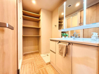 広々とした洗面スペースが魅力です。大型のミラーと収納棚が備わり日常使いに便利な設計です。明るい照明で使い勝手が向上しています。飽きのこないシンプルなデザインです。収納力も十分確保されています。