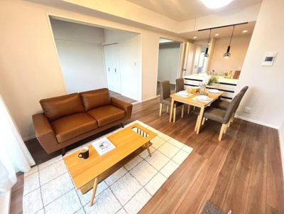 開放感のあるリビングはナチュラルな色合いでまとめられ明るい空間が広がっています。木目調の床と家具が調和し落ち着いた雰囲気を演出しています。ダイニングエリアも隣接していて動線がスムーズです。