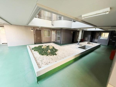 広々とした共用スペースが印象的です。中央には緑と石が配置されており開放的な雰囲気です。天井も高く明るさが感じられます。各部屋へのアクセスも便利な造りとなっています。清潔感のある共用部分です。