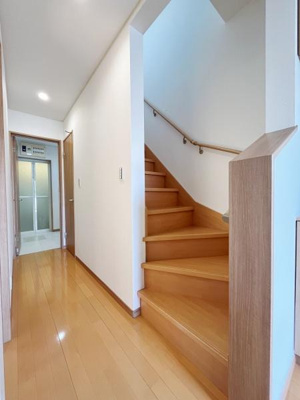 明るいフローリングと白い壁の組み合わせがすっきりとした印象を与えます。階段部分も手すり付きで安心です。廊下の奥には水まわり設備も配置されています。動線の良いレイアウトが魅力です。