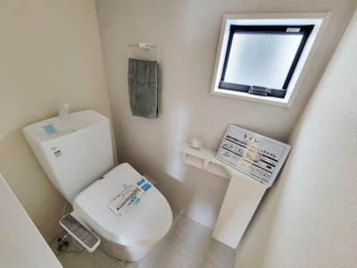 明るい雰囲気のトイレです。窓付きで自然光を取り入れやすく換気もしやすい設計となっています。清潔感のある内装で機能的な設備が整っています。ペーパーホルダーやタオル掛けも備わっています。