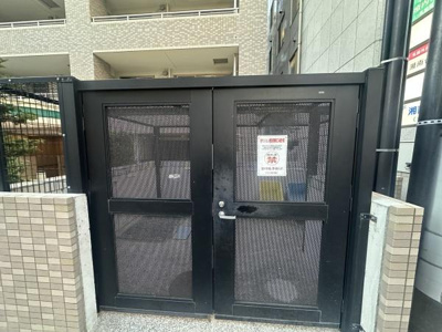 しっかりとした金属製の扉が設置されており外部からの視線にも配慮されています。建物と調和したカラーで統一感があります。細かなメッシュ仕様で清潔感のある共用スペースです。サインも見やすく掲示されています。