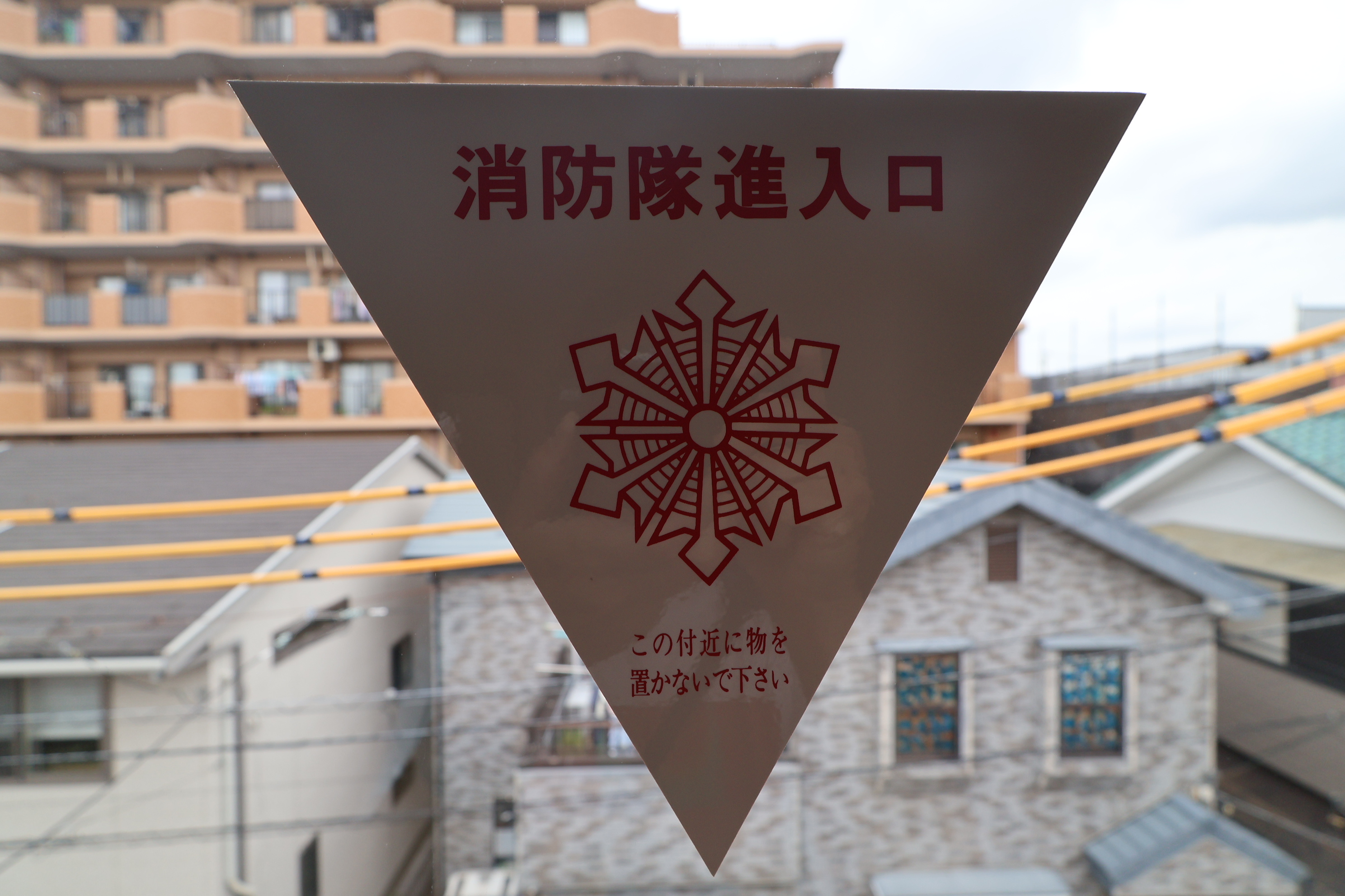 窓に貼ってある三角のシール▼(消防隊進入口)に防犯フィルムを...の画像